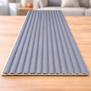 Grey fluted wall panel with vertical ribbed design displayed on a wooden table in a modern interior setting.