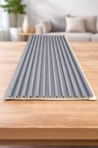 Grey fluted wall panel with vertical grooves displayed on a wooden table in a modern living room.