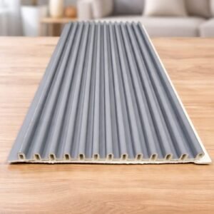 Grey fluted wall panel with vertical grooves displayed on a wooden table in a modern living room.