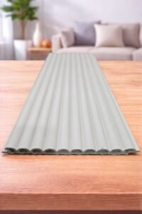 White fluted wall panel with a vertical ribbed design displayed on a wooden table