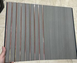 Grey wood-finish fluted panel with vertical grooves and rose-gold metallic lines