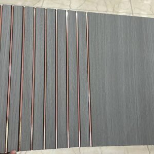 Grey wood-finish fluted panel with vertical grooves and rose-gold metallic lines