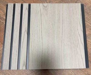 Light beige wood-texture decorative wall panel with vertical grooves and subtle dark grain detailing.