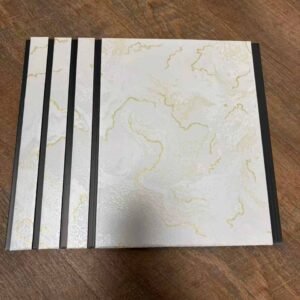 White marble finish fluted wall panel with elegant golden vein patterns and dark grey vertical grooves.