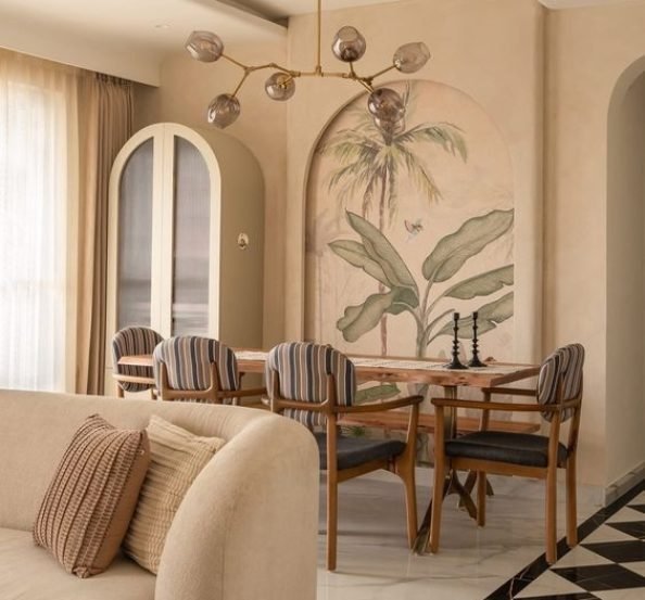 Elegant modern dining and living room interior featuring a botanical mural, arched wall design, beige sofa, striped dining chairs, warm neutral tones, and a stylish pendant light